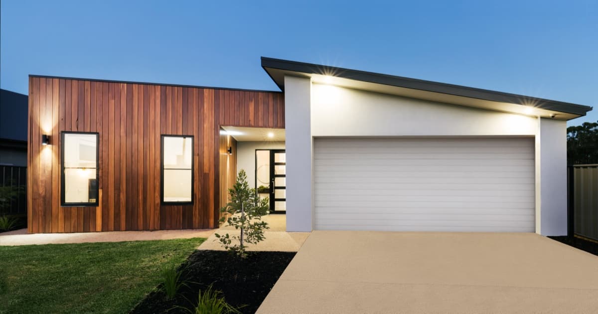 New home exterior with timber cladding and wall lights at dusk